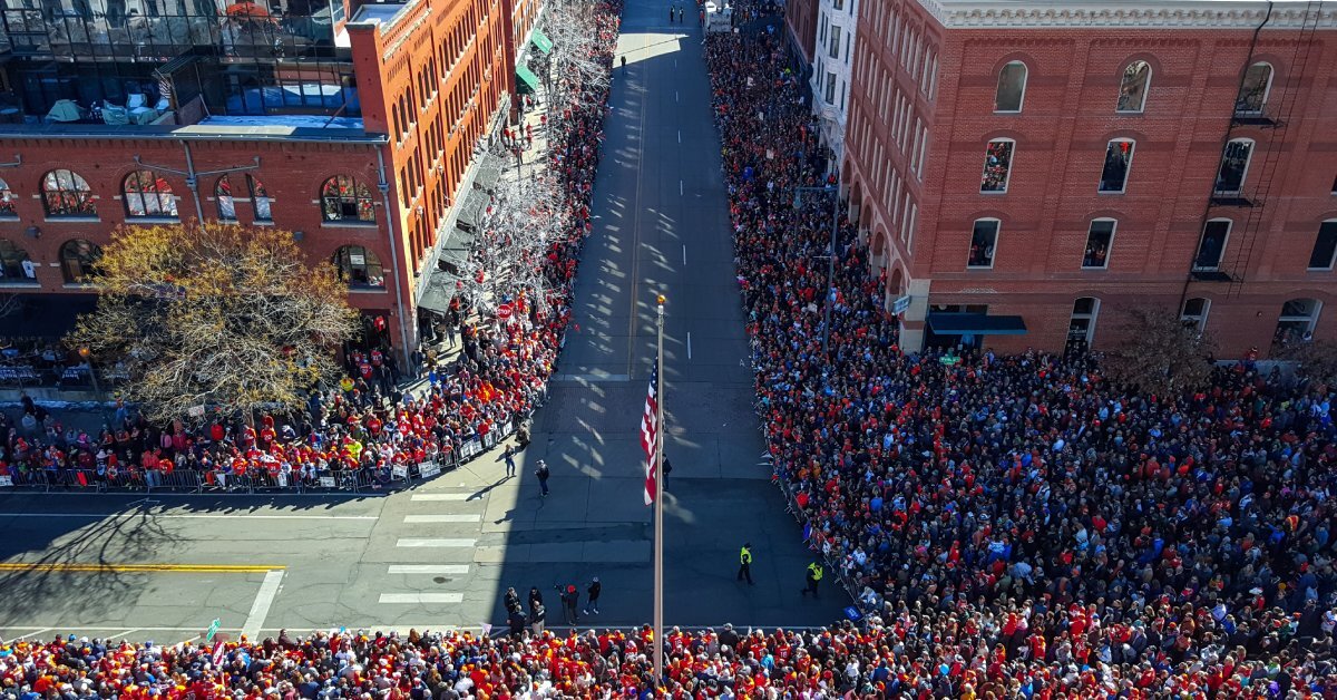 An aerial view of a large parade going through Denver, Colorado with lots of people crowding the streets.