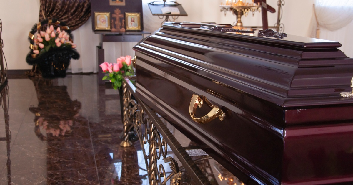 A close up of a table with small candles and flowers surrounding a small, blank, funeral frame.