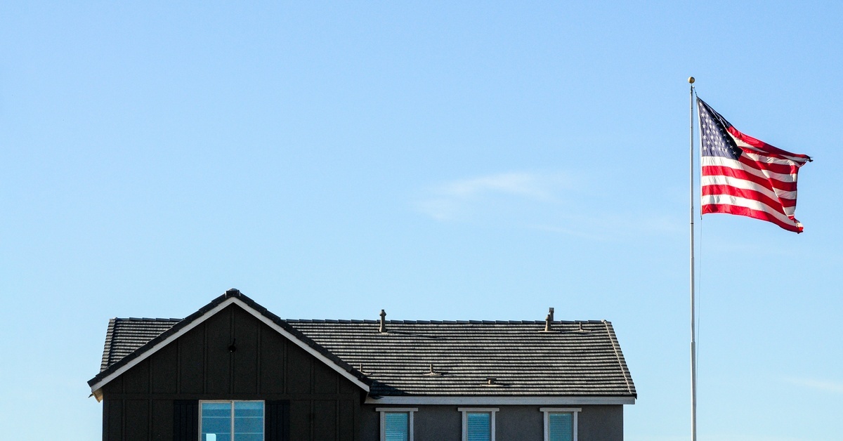 How To Select the Right Height for an In-Ground Flagpole In the distance, there's a large two-story home with an incredibly tall flagpole and American flag in front of it.